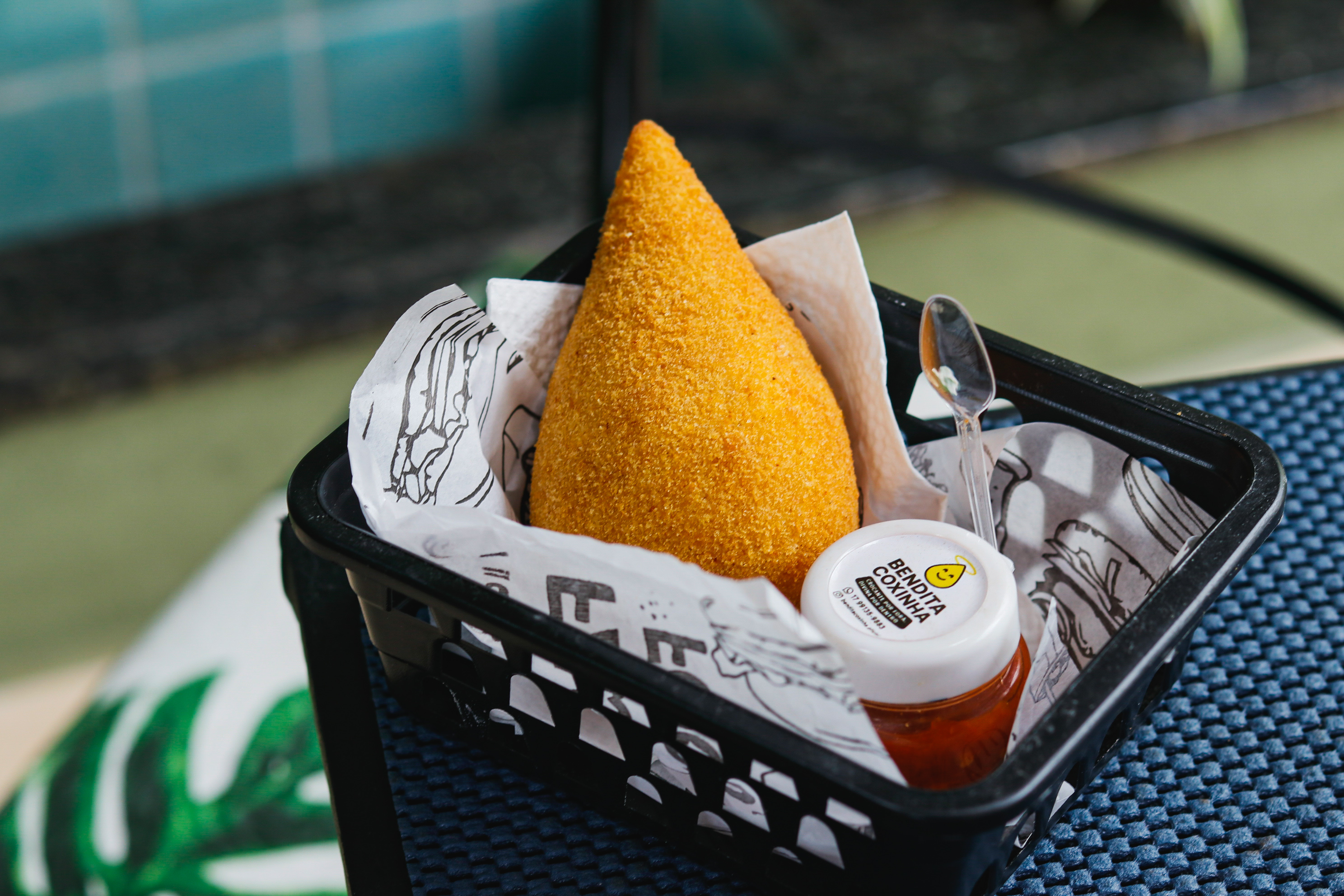 Coxinha dourada e crocante servida em cesta com molho